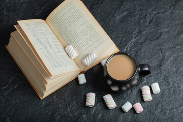 A cup of coffee with marshmallows and book