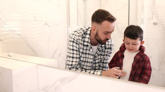 Start good oral habits early. Portrait of happy family father and son child boy brushing teeth in the bathroom. Morning routine with toothbrushes, father s day concept