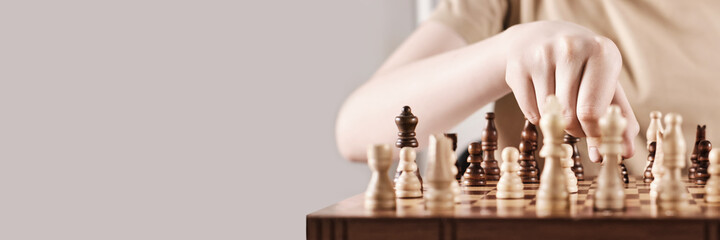 Banner with Faceless boy develops game strategy. Hand holds chess piece and makes a move, selective...