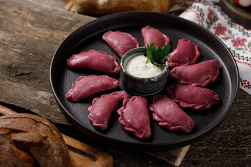 Delicious traditional Russian dumplings, handmade dough painted with beets. Still life on a wooden...