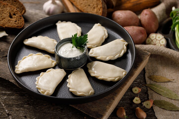 Appetizing traditional Russian dumplings, hand-made with potatoes. Still life on a wooden board. Close-up.