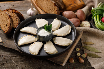 Appetizing traditional Russian dumplings, hand-made with potatoes. Still life on a wooden board. Close-up.