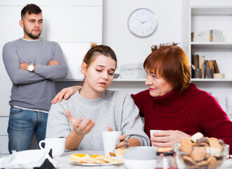 Senior woman calming chagrined girl during her quarrel with boyfriend