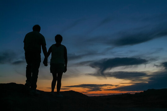 Romantic couple silhouetted against a beautiful night sky on mountain top