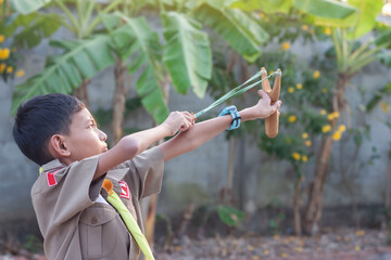 Asian boy holding and playing shooting wooden catapults in the morning.