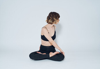 Obraz premium A woman in leggings sits cross-legged on the floor and turns to the sides