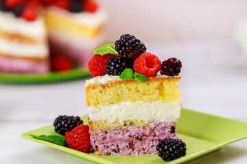 Piece of berry cake decorated with fresh raspberries and blackberries.