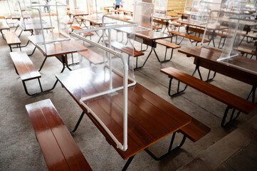 Group of plastic partition setting on table in canteen for reduce and protection the COVID-19 virus spreads in pandemic. Focus to the table in the center of this picture.