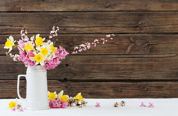 spring flowers in white jug on wooden background
