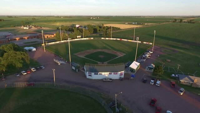 Drone shot over midwest small town baseball game in the summer surrounded by fields