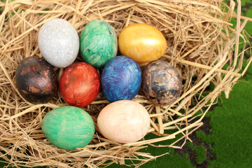 straw basket with easter eggs on grass background