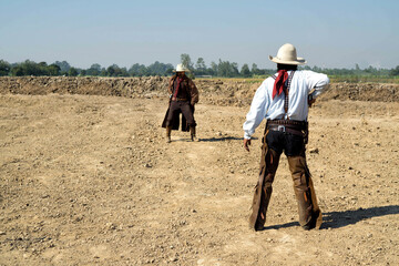Two cowboy outfit costume with a gun held in the hand on gun fight against smoke and sun light on...