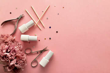 A set of manicure tools and accessories on a pink background with flowers and rhinestones. Nail care. Flat lay. Copy space. Women's Day. March 8 - obrazy, fototapety, plakaty