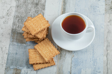 Aroma cup of tea with tasty crackers on a wooden table