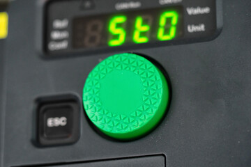 Close-up on a circular green frequency converter control button.