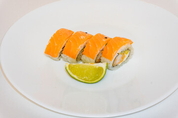 Sushi rolls philadelphia with prawns and slice of lime lie on white plate. Japan kitchen, european sushi rolls with cream cheese, salmon and prawn