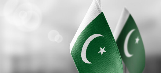 Small national flags of the Pakistan on a light blurry background - obrazy, fototapety, plakaty