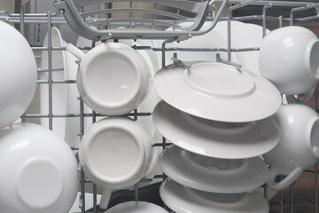 white plates and mugs after cleaning in the automatic dishwasher