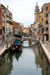 Small canal with traditional gondolas seen in the old town of Venice, Italy