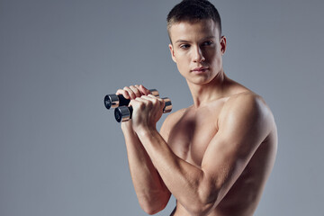 Fototapeta na wymiar cute sporty man with dumbbells in hands cropped view muscular body close-up