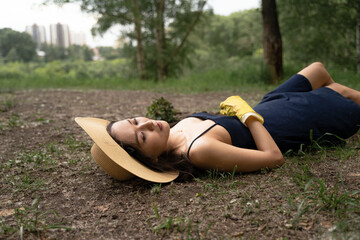 a girl of Asian appearance in a straw hat and yellow gloves lies on the ground in a dress