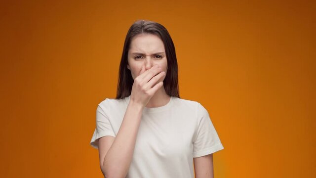 Close up of a woman closing nose bacause of a bad smell