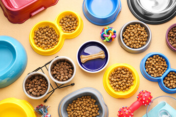 Bowls with pet food and accessories on color background, closeup