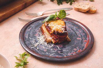 Plate of tasty baked eggplant with cheese on color background