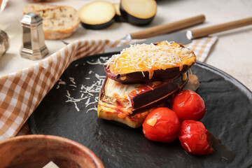 Tasty baked eggplant with cheese and tomatoes on light background