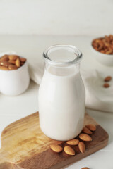 Bottle of tasty almond milk on light background