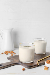 Glasses of tasty almond milk on light background