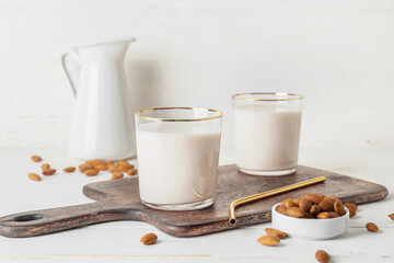 Glasses of tasty almond milk on light background