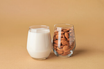Glass of tasty almond milk and nuts on color background
