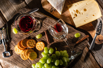 Tasting cheese platter with grapes and fruits on an old wooden table. Food for wine and romantic, cheese delicacies. Menu design horizontally. View from above.