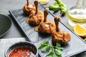 Board with tasty chicken lollipops on dark background
