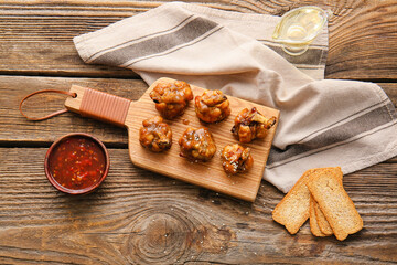 Board with tasty chicken lollipops on wooden background