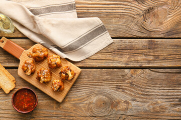Board with tasty chicken lollipops on wooden background