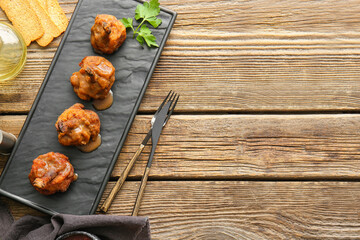 Board with tasty chicken lollipops on wooden background