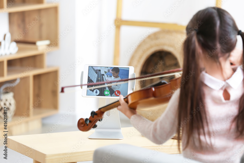 Wall mural Little girl studying music with her friend online at home