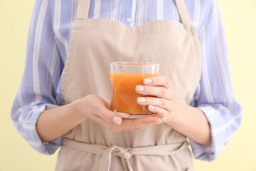 Woman with glass of healthy carrot smoothie on light background, closeup