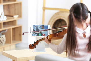 Little girl studying music with her friend online at home