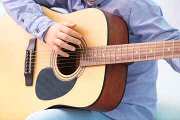 Fototapeta na wymiar Little boy playing guitar at home, closeup