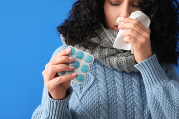 Sick young woman with pills on color background