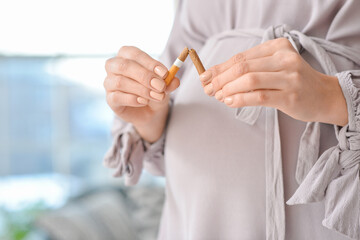 Young pregnant woman with broken cigarette, closeup. Concept of refusing from bad habit