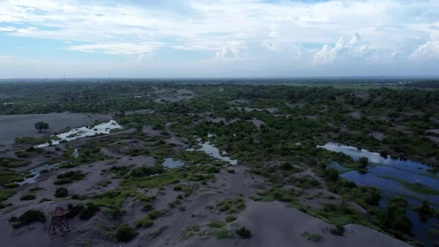 Aerial Drone View Flight over desert with puddles and some green trees in the mountains