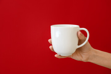 Hand with cup on color background