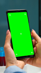 Close up of doctor's hand holding phone with green screen sitting at desk in biological laboratory while nurse bringing blood samples. Scientist using smartphone with mockup, chroma key display