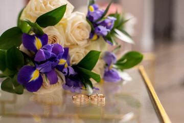 Wedding bouquet of flowers with rings on glass table