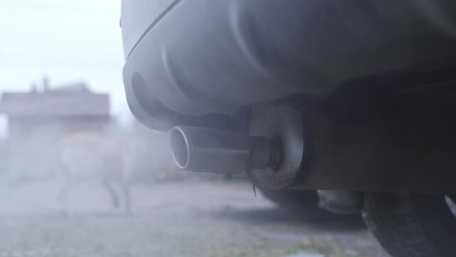 A spectacular detour of a steaming, smoking car exhaust pipe in the morning in slow motion