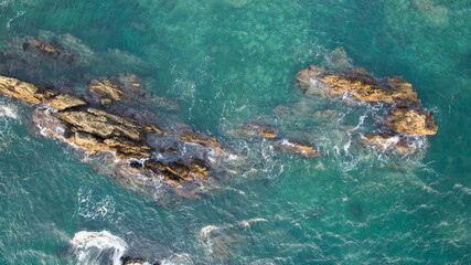 Aerial view of large rocks protruding from the ocean